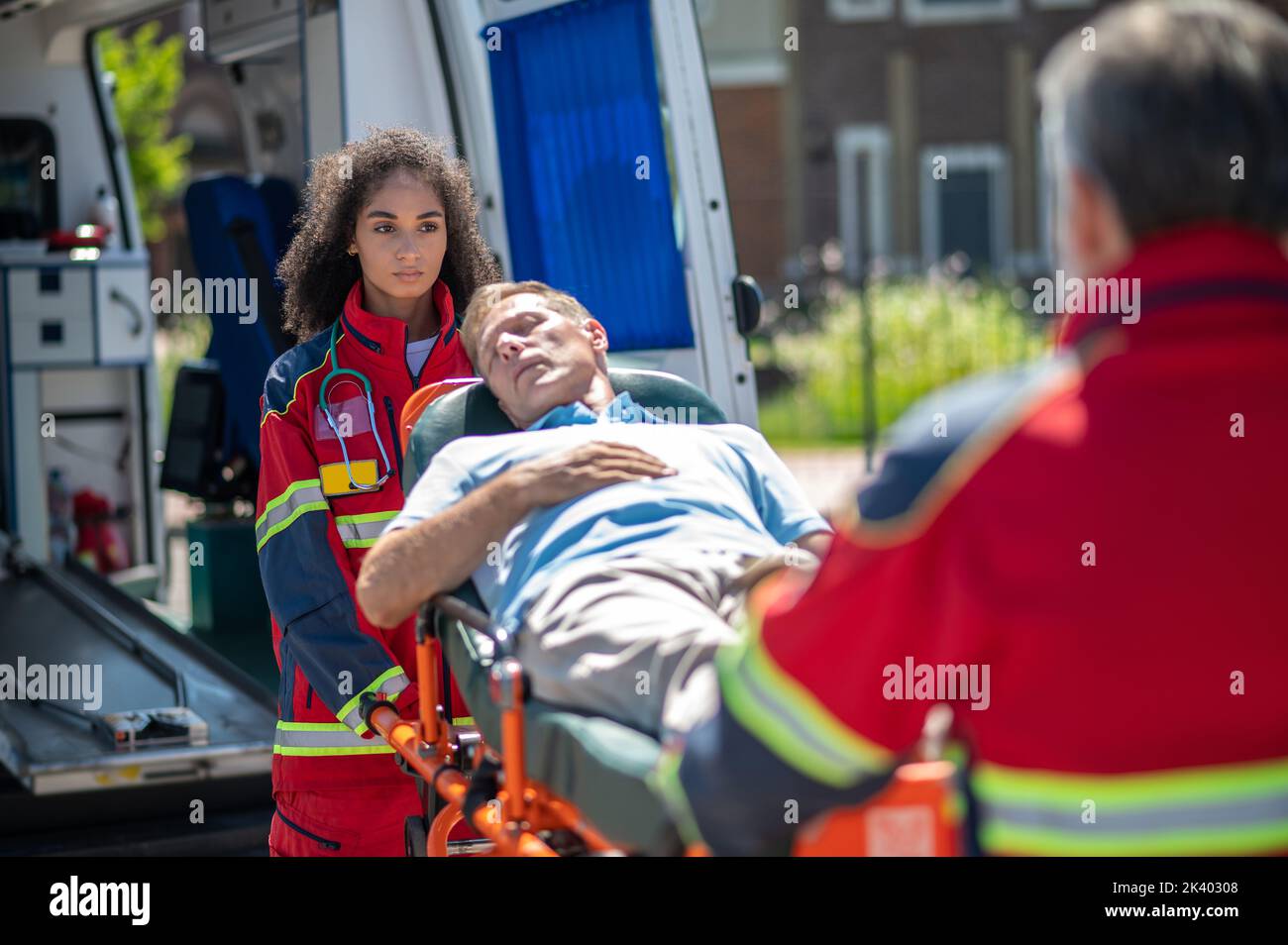 Personale paramedico che trasporta un paziente inconscio all'ambulanza Foto Stock