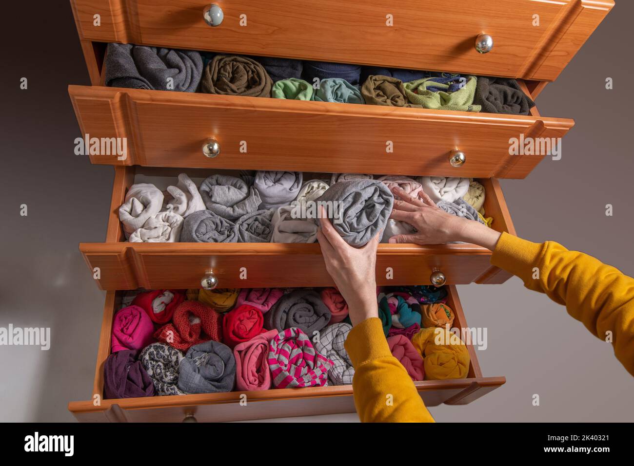 Pulizia e smistamento dei vestiti secondo il metodo giapponese del guardaroba. Cassetti a cassettiera aperti con abiti ritorsibili a magazzino verticali. Vista dall'alto. Foto Stock