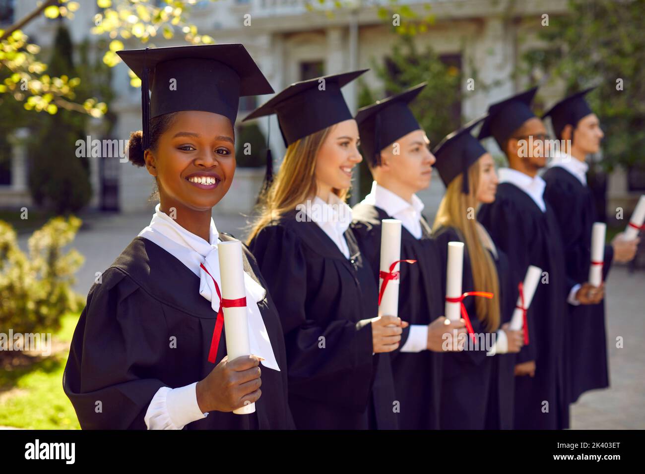 Felice e orgogliosa studentessa dalla pelle scura alla cerimonia di laurea all'università. Foto Stock