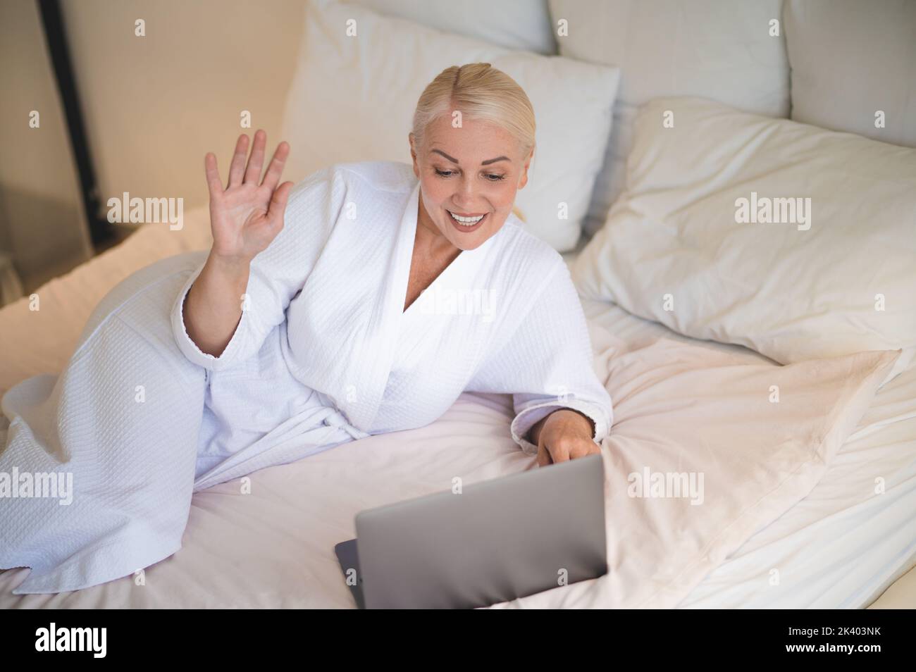 Sorridente bella signora matura felice che comunica con qualcuno online Foto Stock