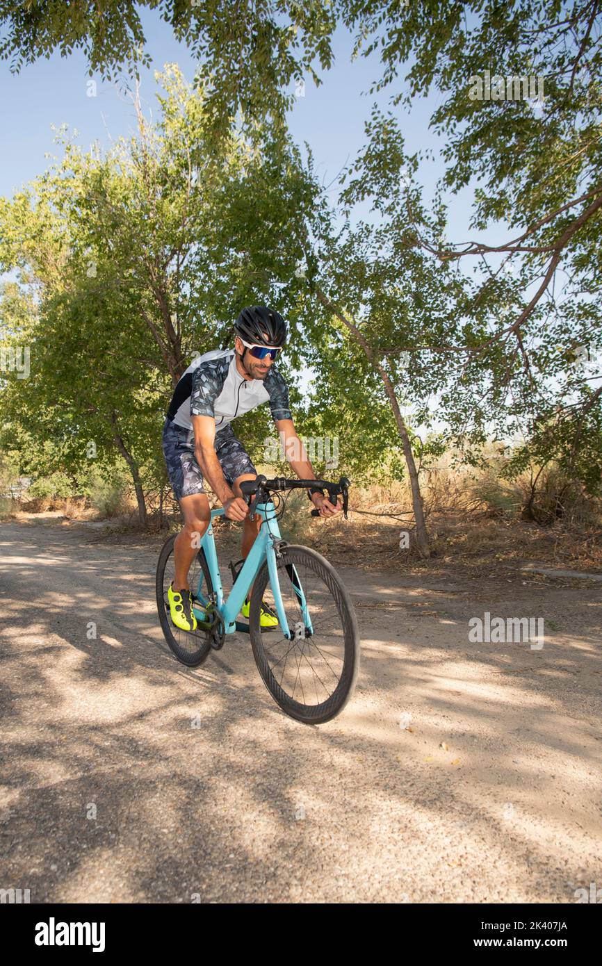 Ciclista pedalando la sua bici da corsa all'aperto con tutte le sue attrezzature: Casco, occhiali da sole, sicurezza. Foto Stock