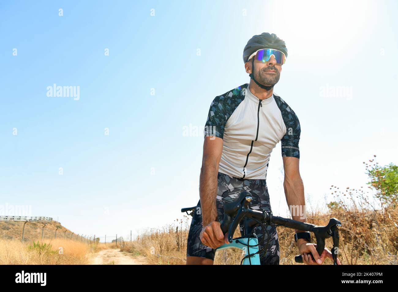 Ciclista pedalando la sua bici da corsa all'aperto con tutte le sue attrezzature di sicurezza: Casco, occhiali da sole, in una giornata di sole Foto Stock