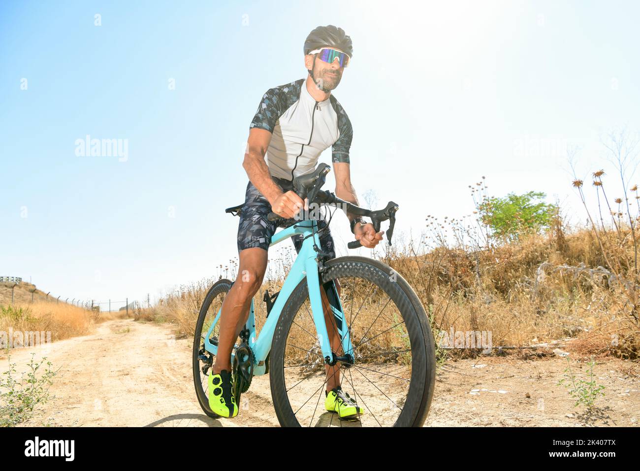 Ciclista pedalando la sua bici da corsa all'aperto con tutte le sue attrezzature di sicurezza: Casco, occhiali da sole, in una giornata di sole Foto Stock