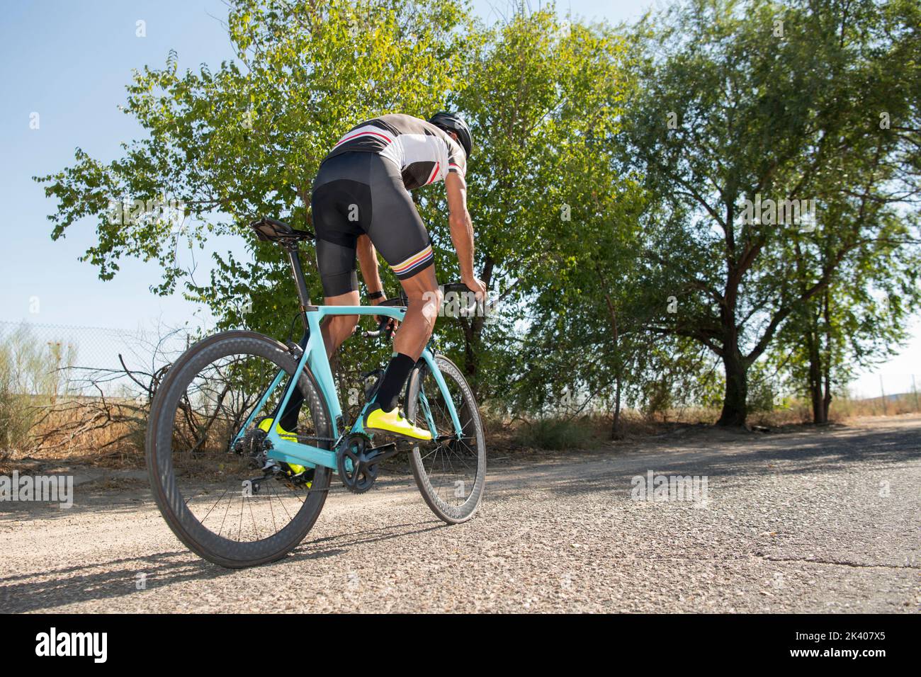 Ciclista pedalando la sua bici da corsa all'aperto con tutte le sue attrezzature: Casco, occhiali da sole, sicurezza. Foto Stock