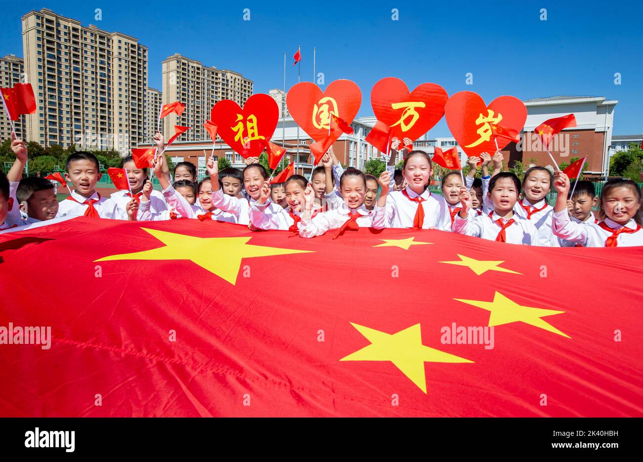 HAI'AN, CINA - 29 2022 SETTEMBRE - gli studenti delle scuole primarie posano con bandiere nazionali per celebrare il 73rd° anniversario della fondazione del popolo Foto Stock