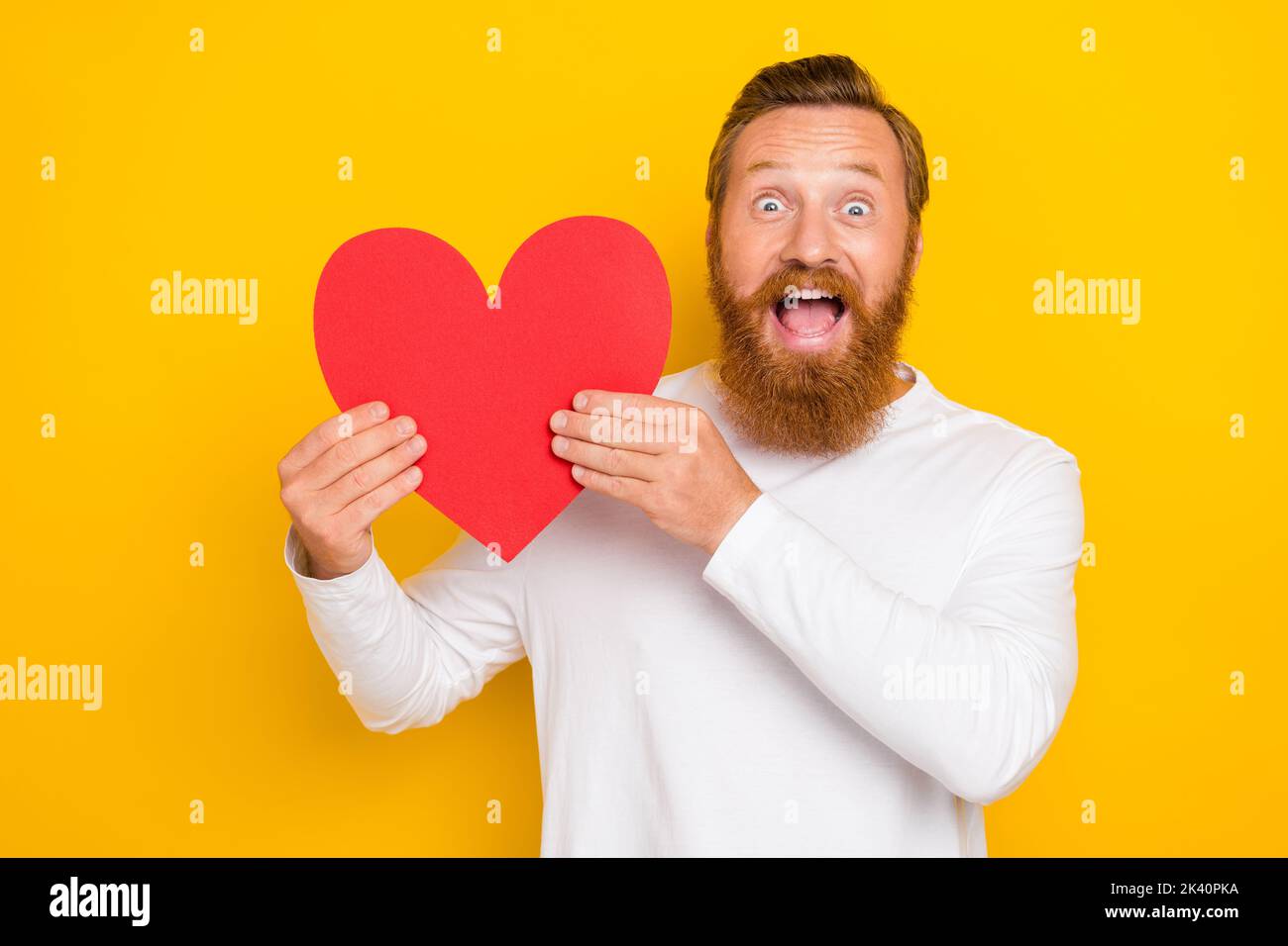 Foto di barba zenzero uomo tenere cuore indossare camicia bianca isolato su sfondo di colore giallo Foto Stock