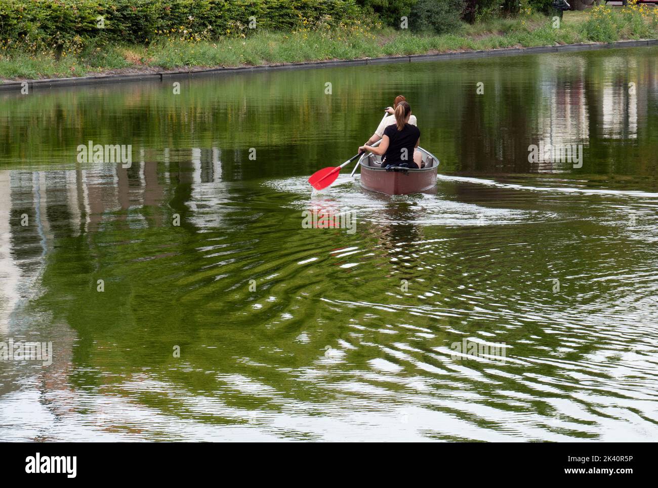 Due ragazze pagaiano una canoa sulle acque di Middelburg, Paesi Bassi Foto Stock