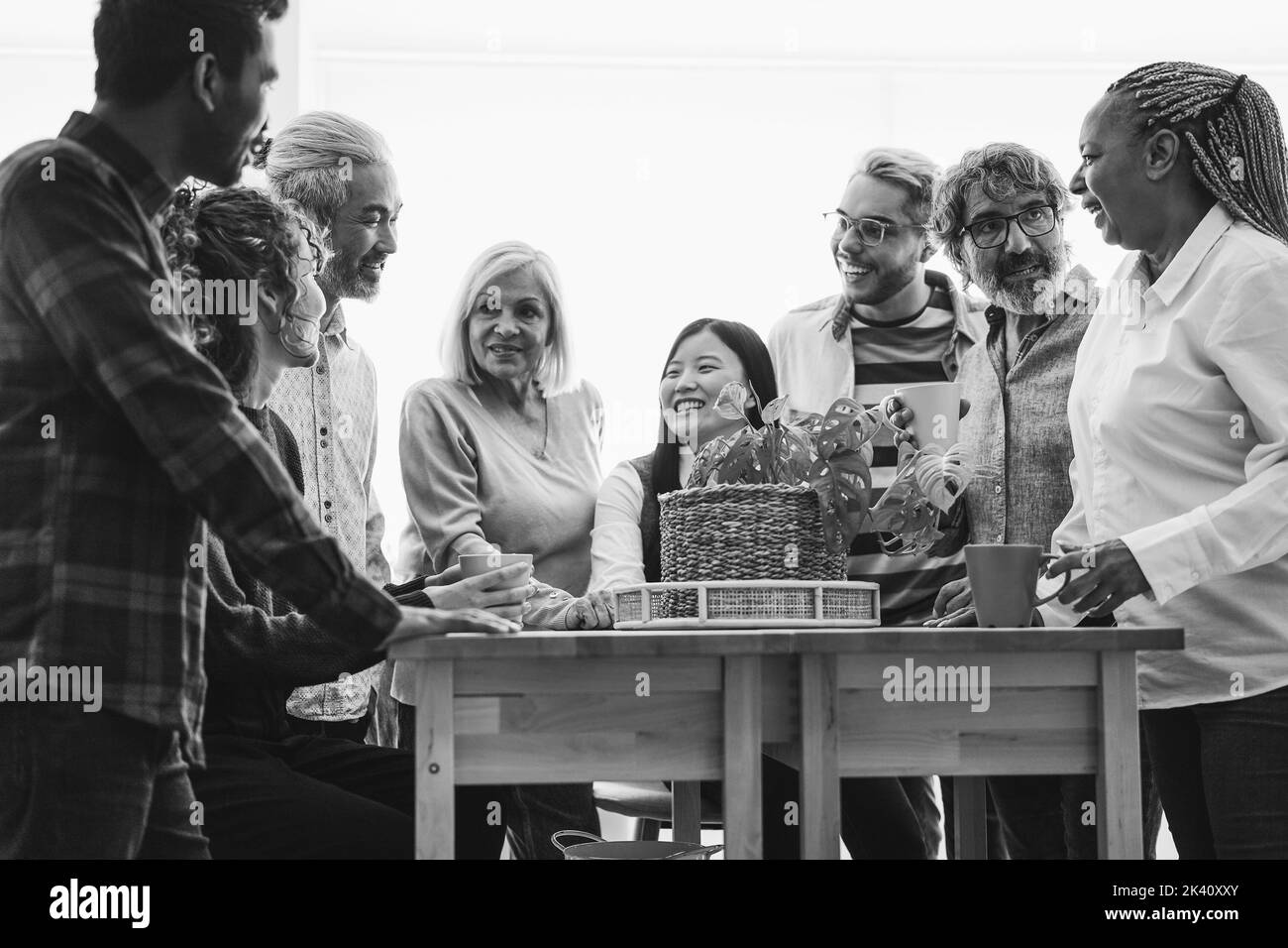 Amici felici multirazziali che hanno divertimento bevendo all'interno della cucina domestica - fuoco principale sull'occhio della donna africana anziana - montaggio in bianco e nero Foto Stock