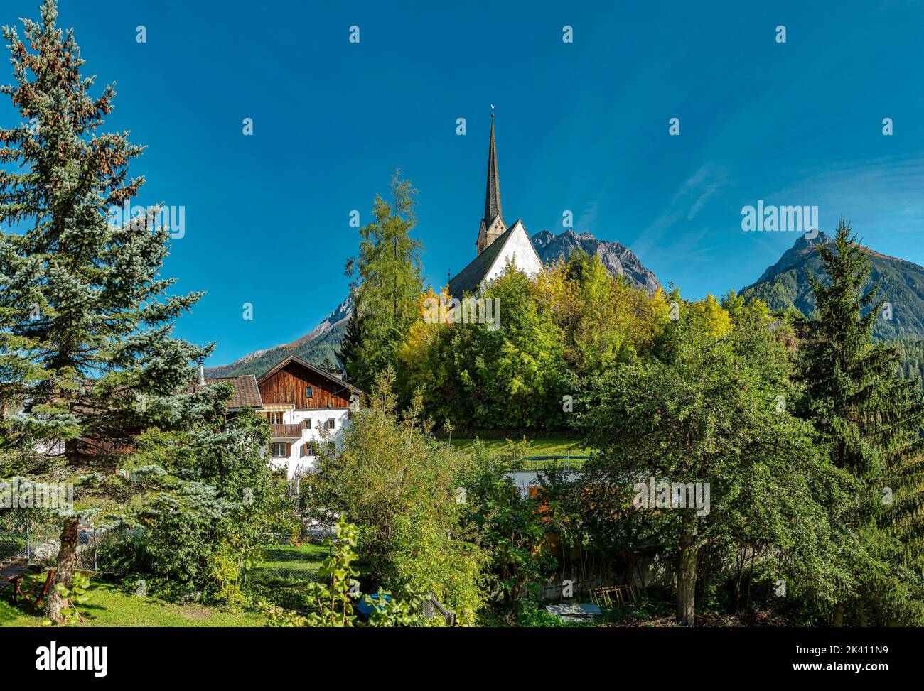 Chiesa in cima ad una collina quasi nascosta da alberi *** Caption locale *** Scuol, Graubünden, Svizzera, chiesa, monastero, foresta, legno, alberi, autunno, Foto Stock