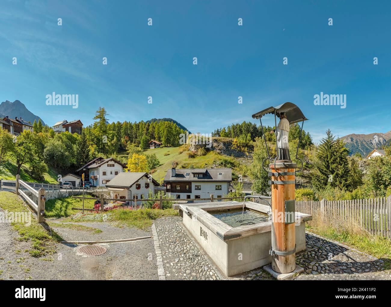 Una fonte d'acqua con una statua Santa *** Caption locale *** Tarasp - Scuol, Graubünden, Svizzera, città, villaggio, campo, prato, alberi, autunno, mount Foto Stock