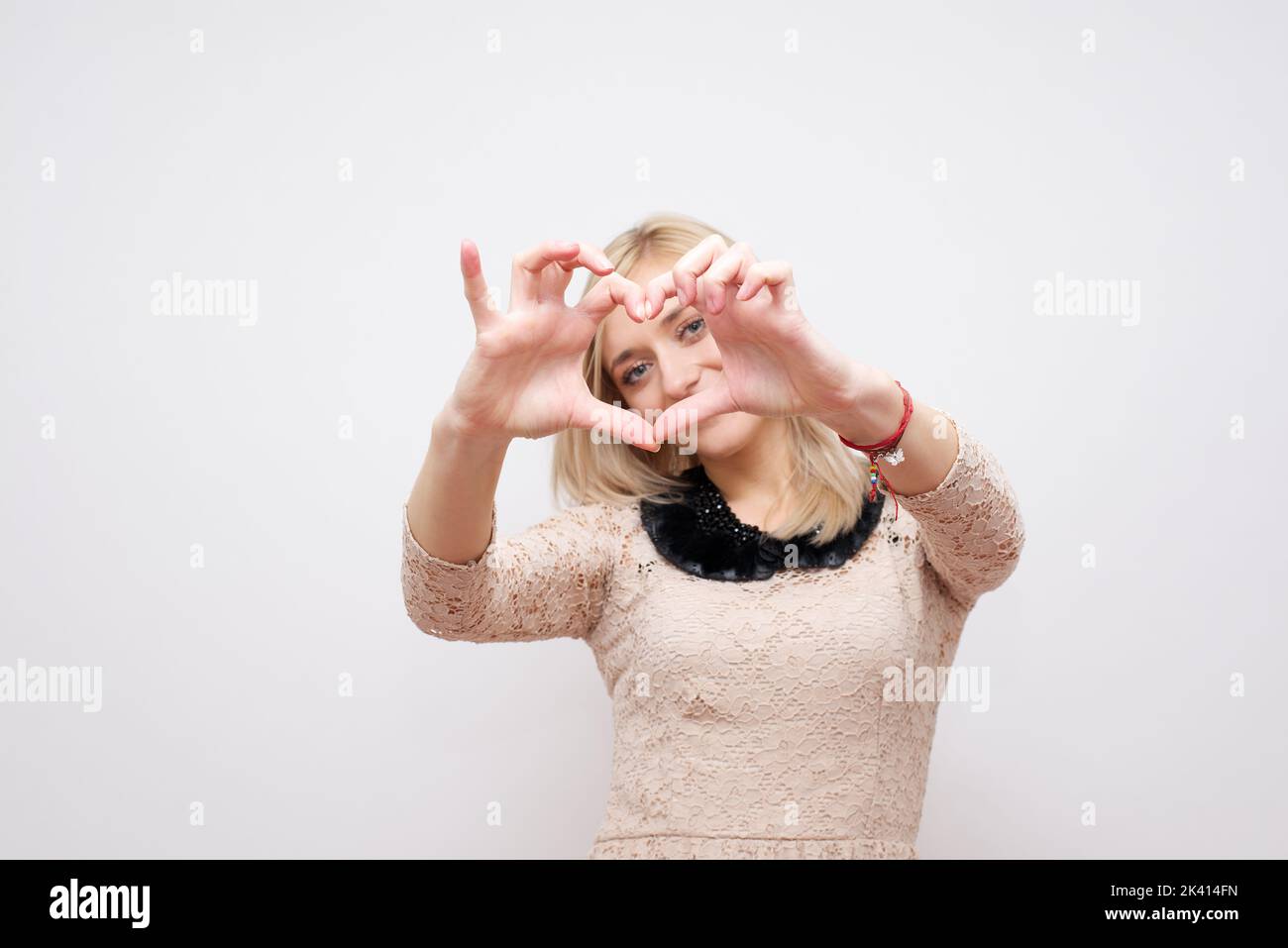 Donna che mostra mani cuore su uno sfondo bianco Foto Stock