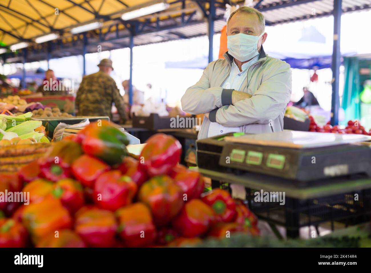 Uomo in maschera acquistare pepe nel mercato Foto Stock