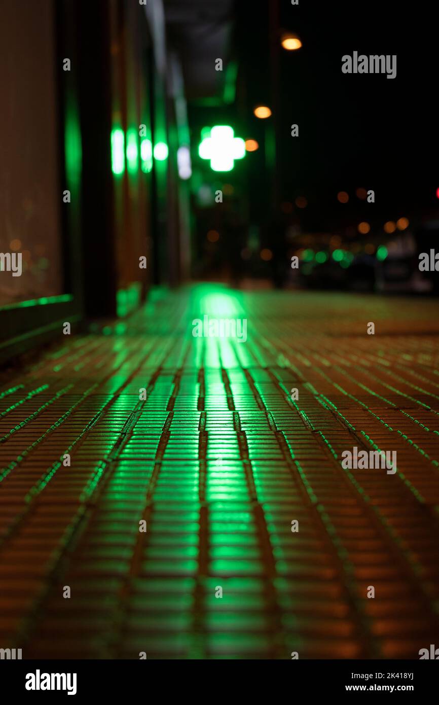 Sfondo urbano. Luci ombre e riflessi in una strada. Luce verde forte riflessa sul terreno Foto Stock