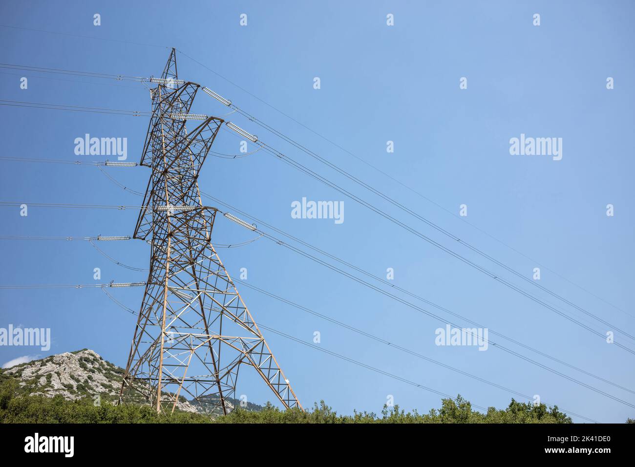 Linee elettriche ad alta tensione e piloni su sfondo blu cielo. Polo metallico con linea trasformatore di potenza. Trasmissione di energia elettrica Foto Stock