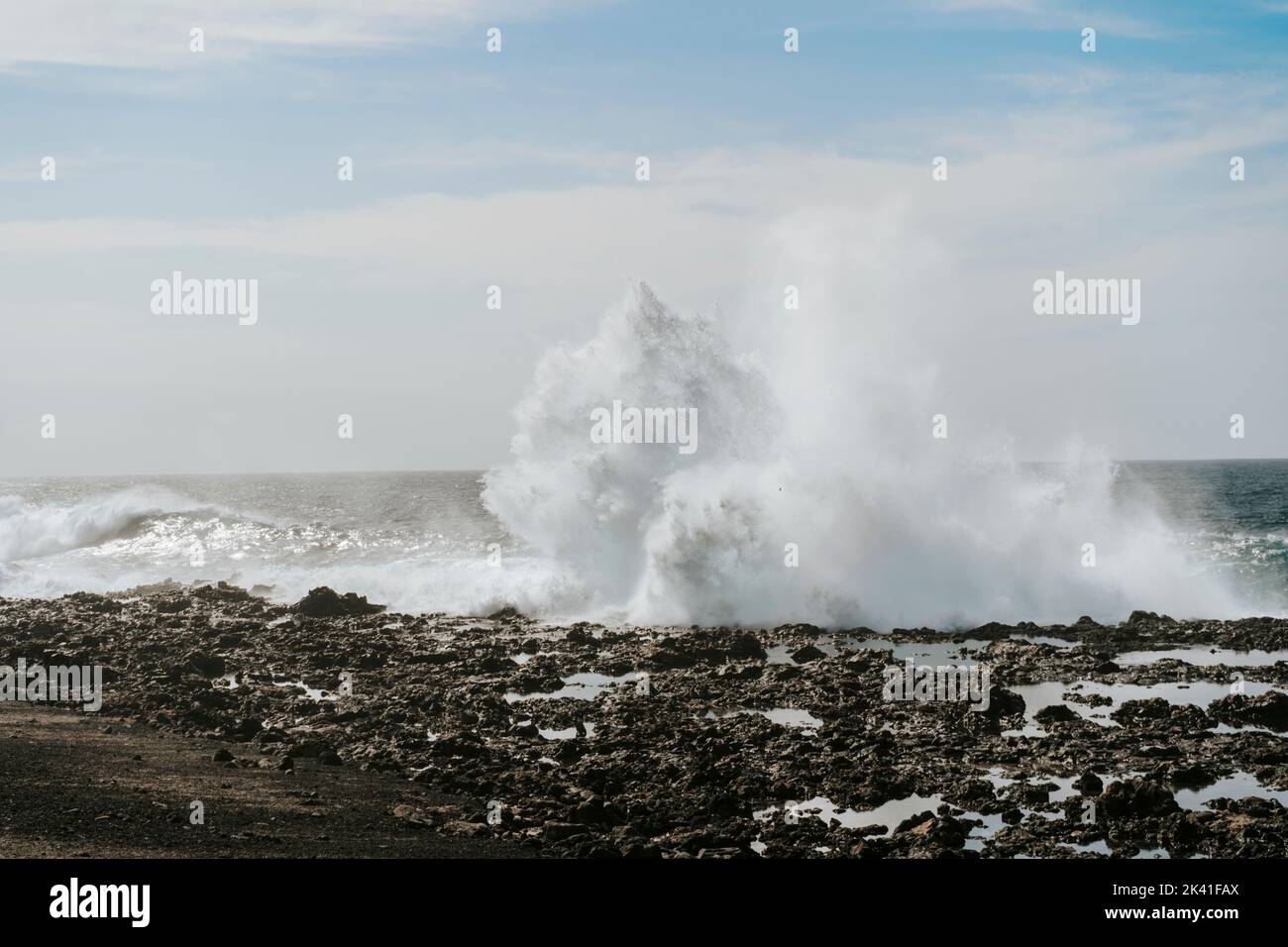 Spruzzi d'acqua sulle rocce vulcaniche nere di Tenesar, Lanzarote, Isole Canarie, Spagna Foto Stock