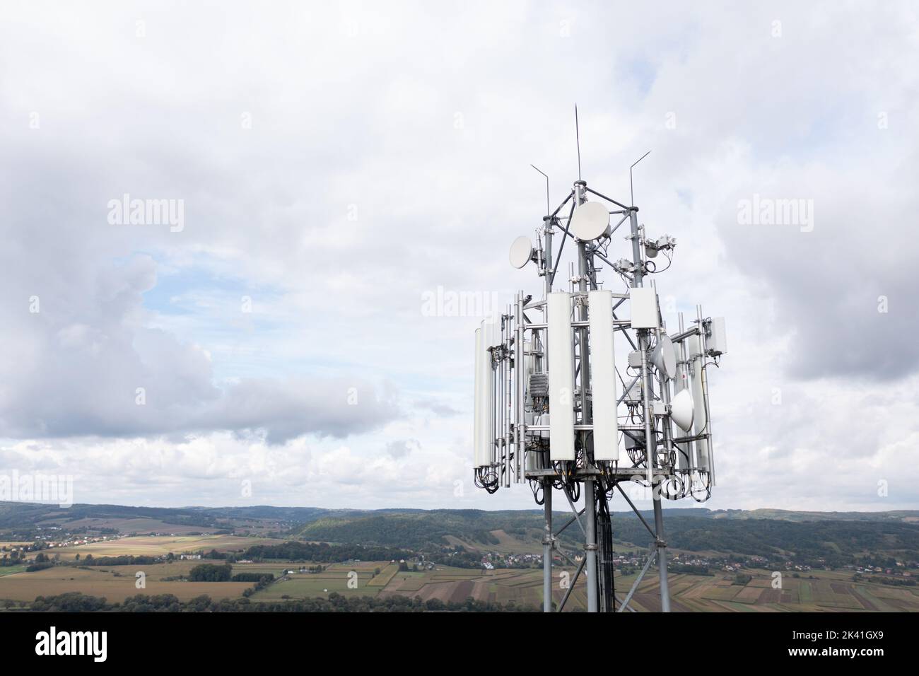 Torre cellulare che trasporta antenne di reti cellulari ricevitore trasmettitore GSM contro cielo nuvoloso e paesaggio, Dynów, settembre 2022. Foto Stock