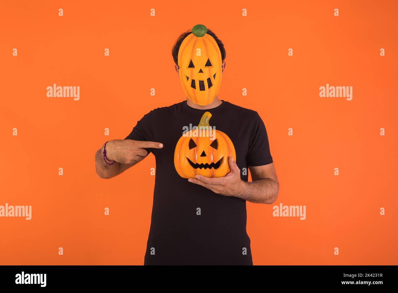 Persona con la maschera di zucca che celebra Halloween, tenendo e indicando una zucca. Concetto di celebrazione, giorno delle ANIME e giorno dei Santi. Foto Stock