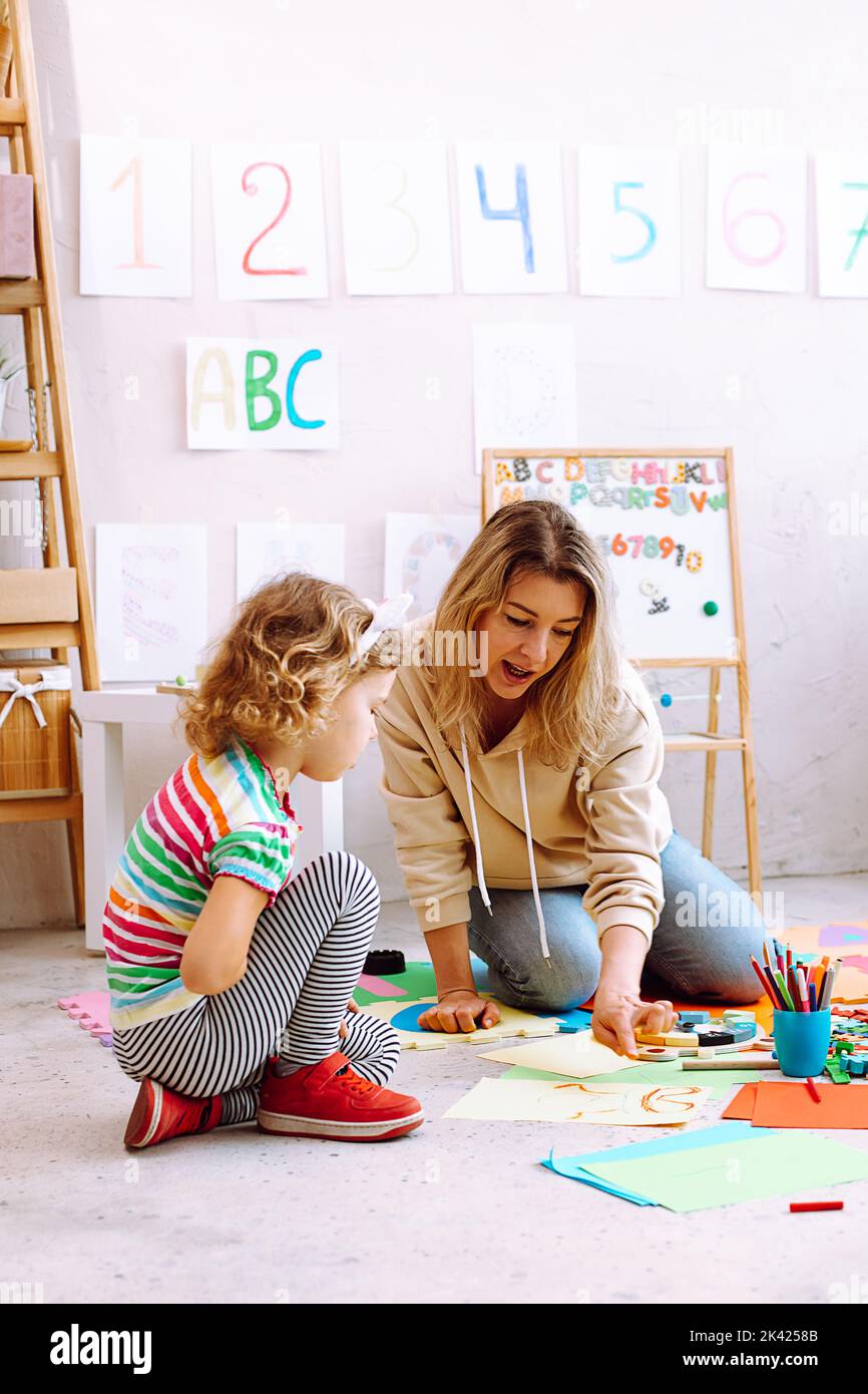 Verticale appassionato insegnante di giocare e dipingere con bambina su cartone, imparare i numeri nella scuola di sviluppo per bambini Foto Stock