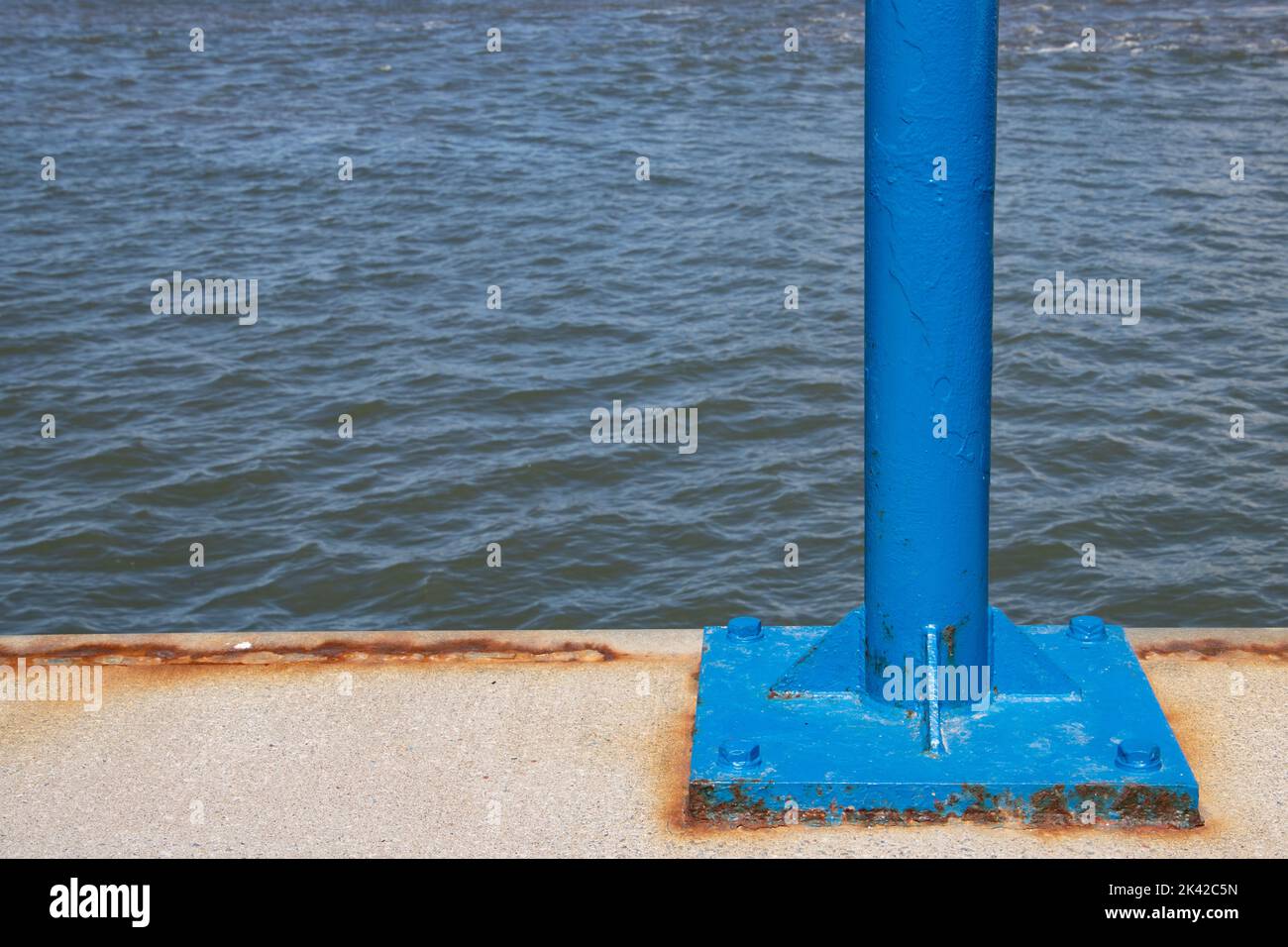 Palo blu in un molo con acqua sullo sfondo e spazio di copia Foto Stock