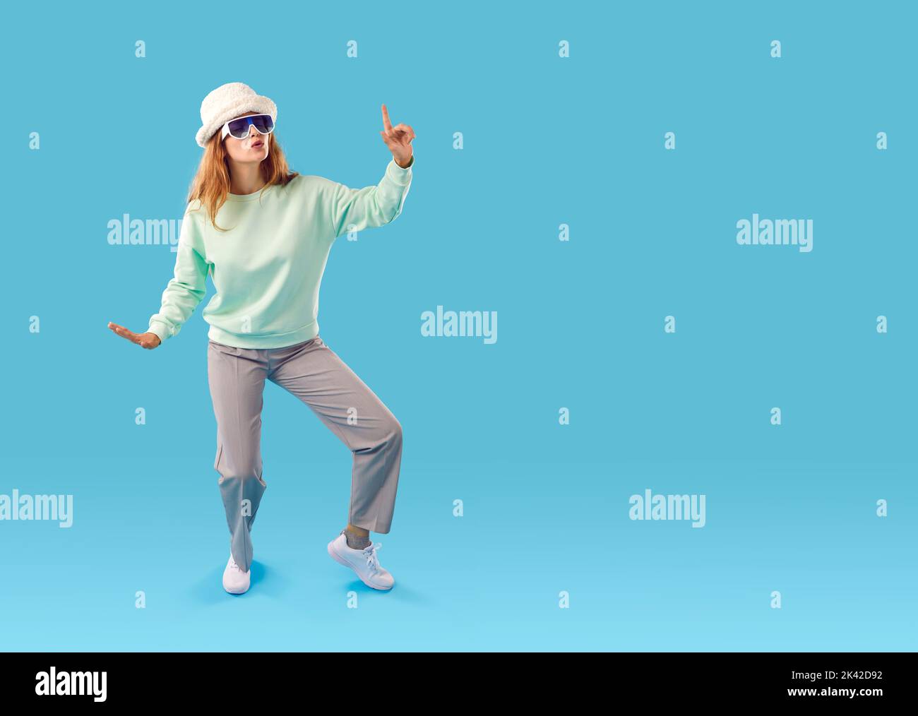 Divertente felice giovane donna in abito alla moda ballare su sfondo blu copia spazio Foto Stock