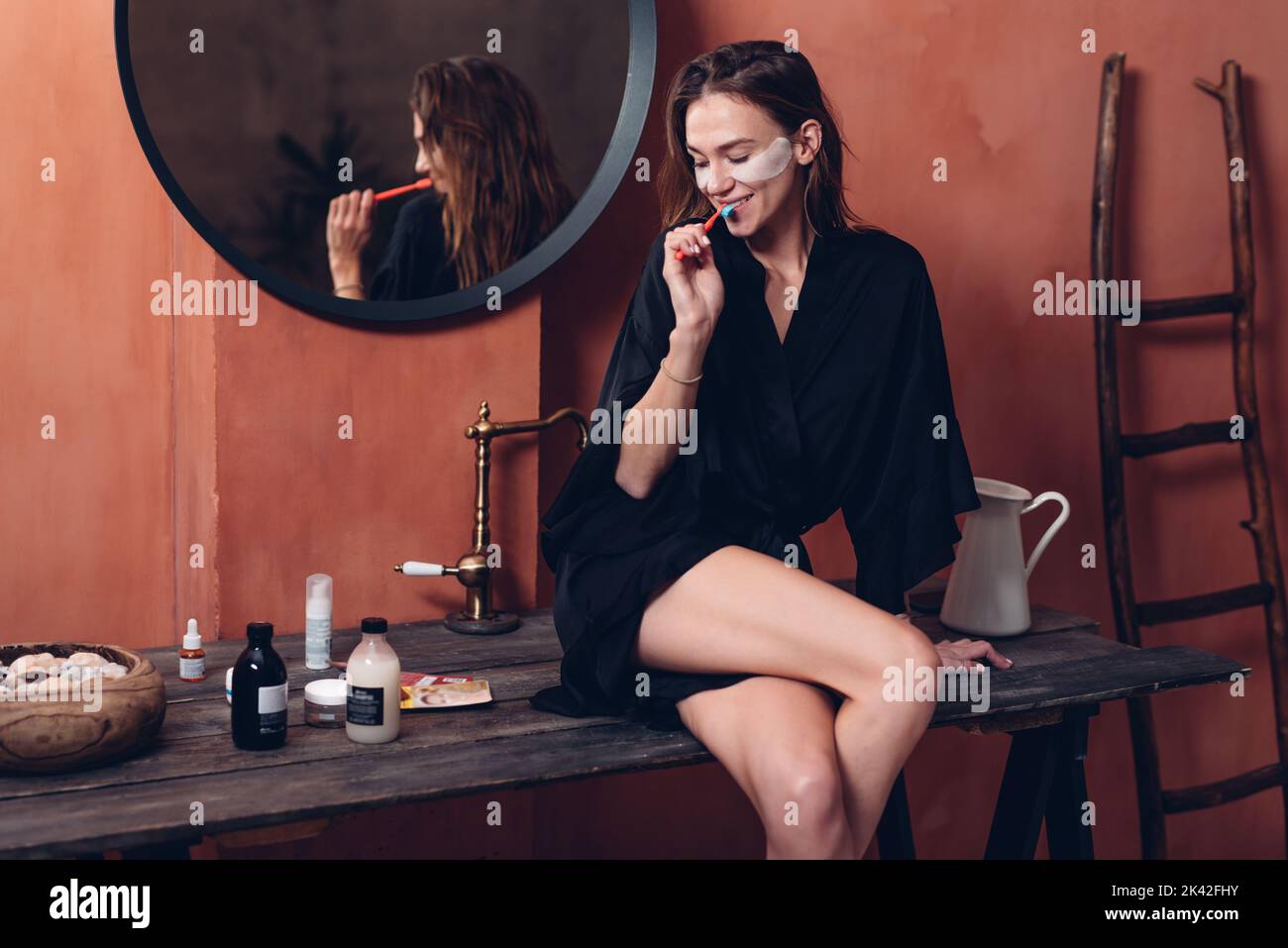Giovane donna con macchie sotto i suoi occhi spazzolandole i denti. Foto Stock