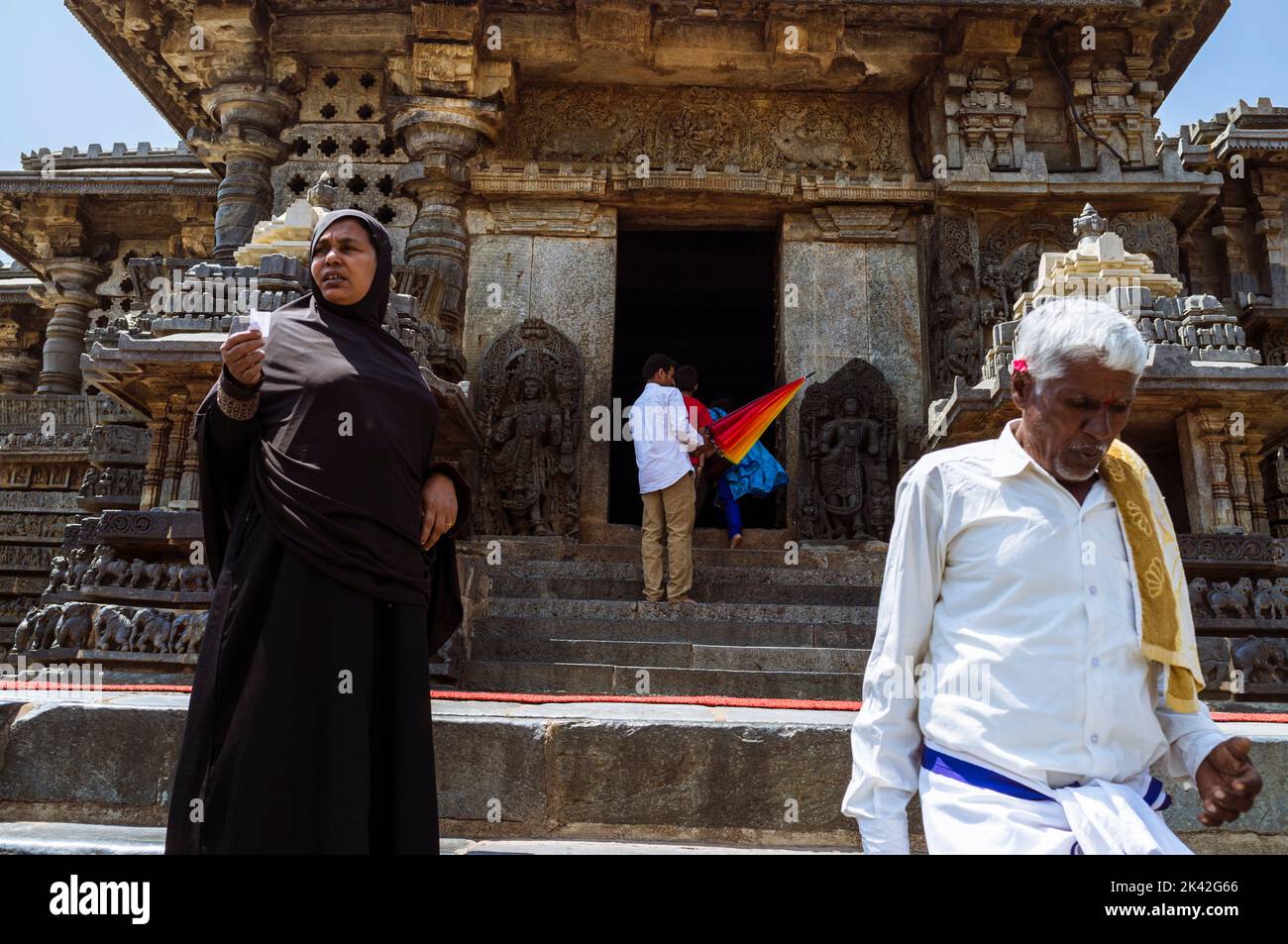 Halebid, Karnataka, India: Un uomo e una donna si trovano fuori dal tempio di Hoysaleswara del 12th° secolo. Foto Stock