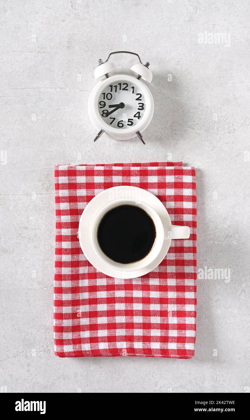 Caffè con sveglia su un tavolo luminoso e tovagliolo rosso, vista dall'alto, spazio per le copie Foto Stock