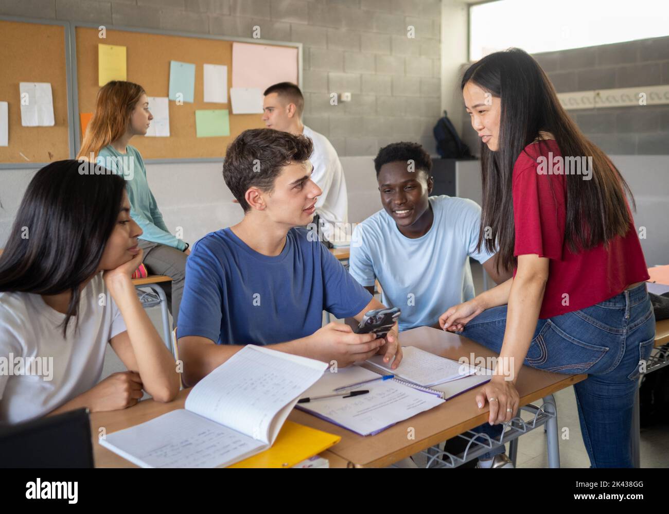 Gruppo di studenti multietnici che parlano in classe durante una pausa. Foto Stock