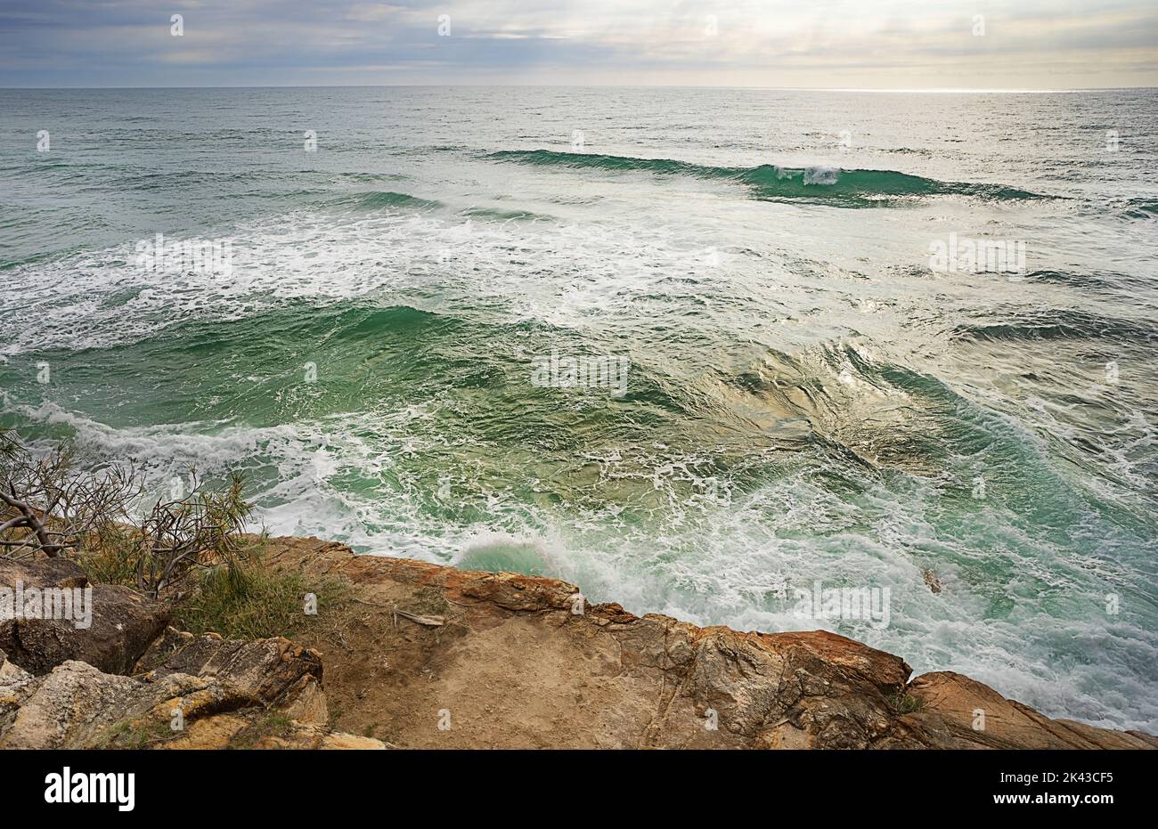 Acque turbolente e turbolente che si infrangono sulle rocce durante l'alta marea lungo una costa rocciosa sulla costa Sunshine, Queensland. Foto Stock