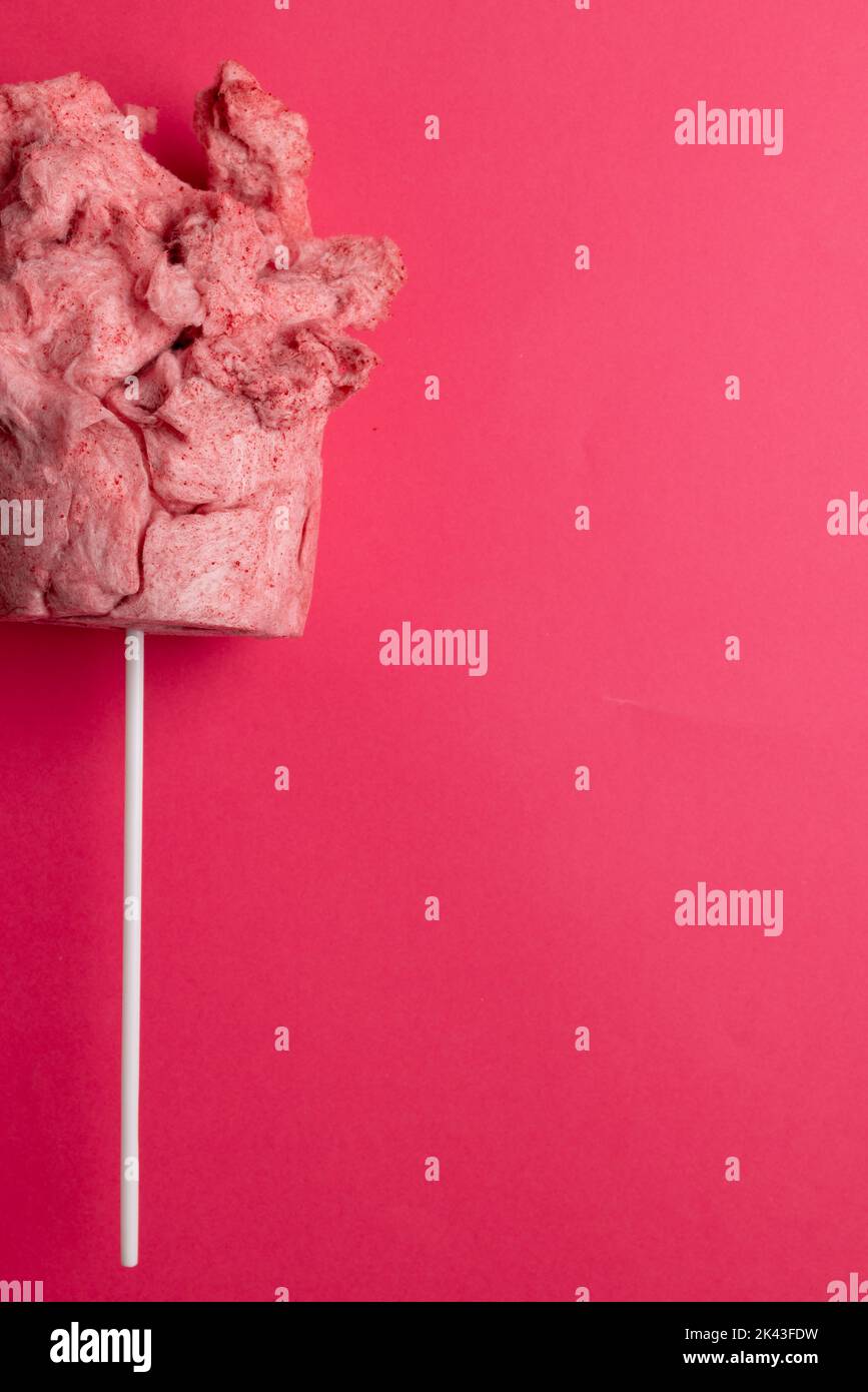 Immagine verticale del filo interdentale di caramella rosa fatto in casa sul bastone, su sfondo rosa con spazio di copia Foto Stock