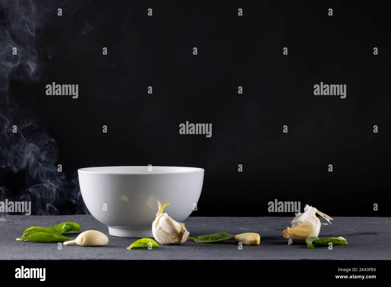 Chiudere il recipiente bianco con i fagioli di edamame e l'aglio con il vapore su fondo nero Foto Stock