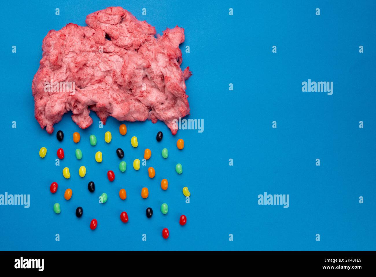 Immagine orizzontale di nuvola di caramelle fatte in casa rosa floss piovoso jelly beans, su blu con spazio copia Foto Stock