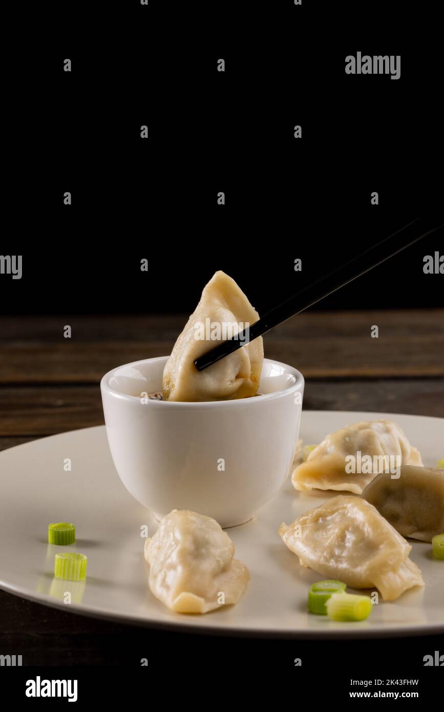 Primo piano di gnocchi asiatici, salsa di soia e bacchette su piatto e sfondo di legno Foto Stock