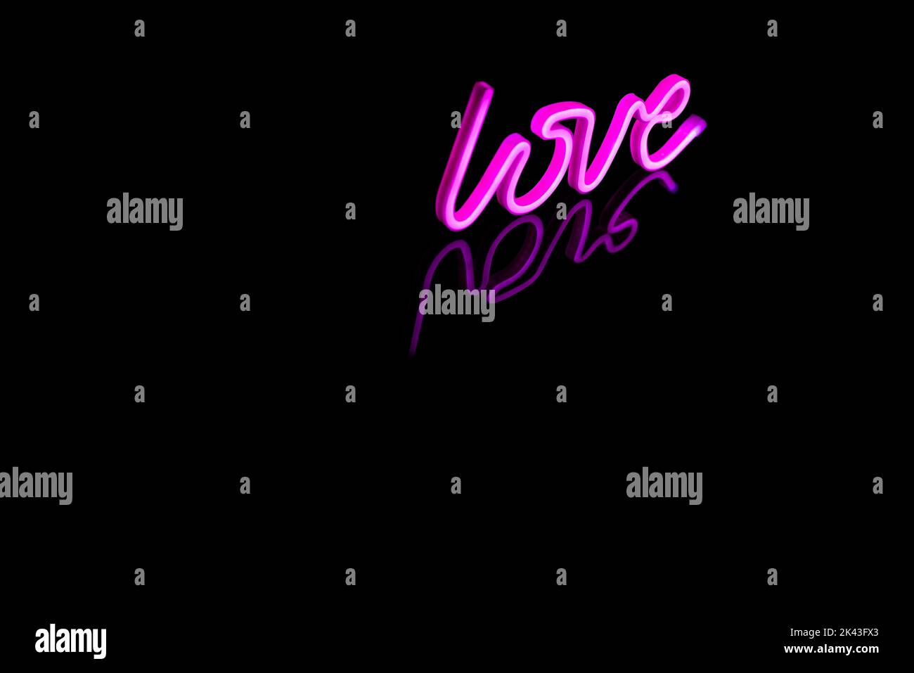 Immagine di un vivace testo amore al neon formato da bacchette rosa su sfondo nero e spazio copia Foto Stock