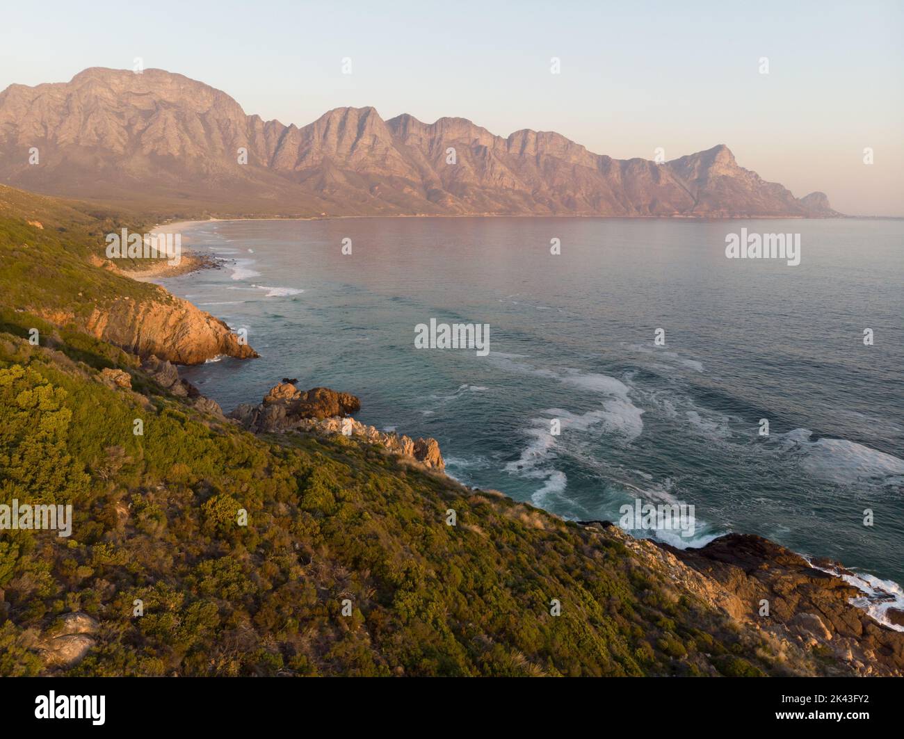 Paesaggio di mare con rocce, montagne, cielo azzurro e orizzonte Foto Stock