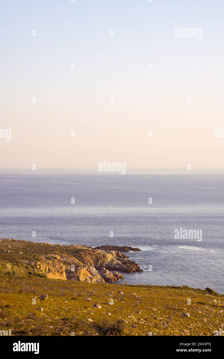 Paesaggio di mare calmo e spiaggia con rocce, cielo azzurro e orizzonte Foto Stock