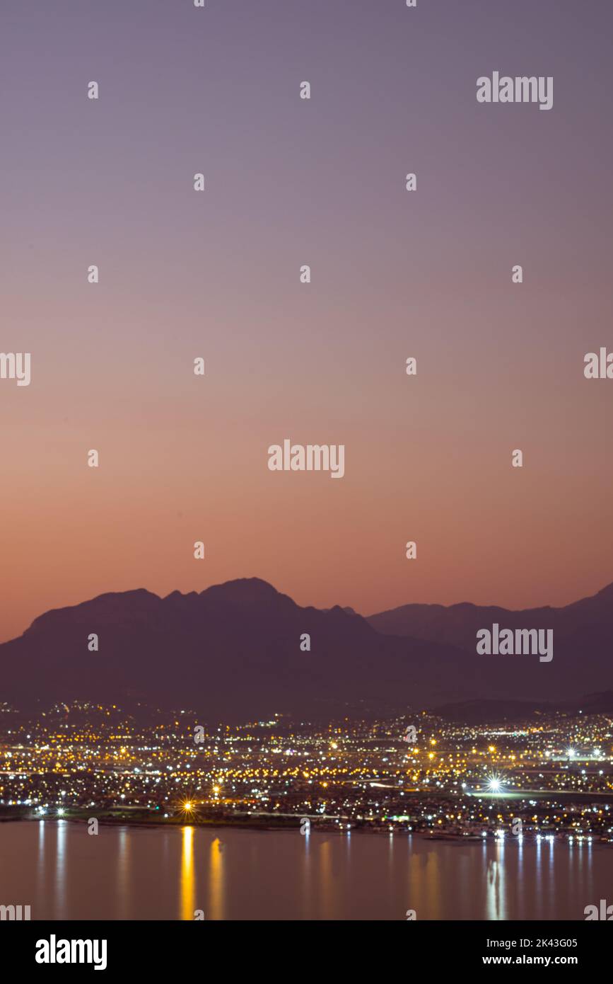 Paesaggio di mare, riva del mare con le luci della città, montagne, cielo senza nuvole al tramonto e all'orizzonte Foto Stock