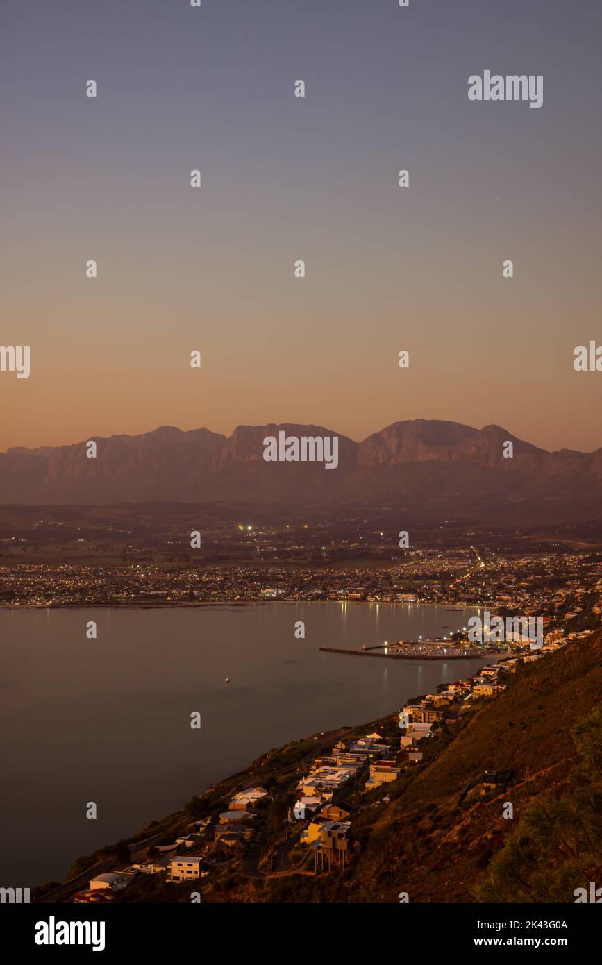Paesaggio di mare, riva del mare con le luci della città, montagne, cielo senza nuvole al tramonto e all'orizzonte Foto Stock