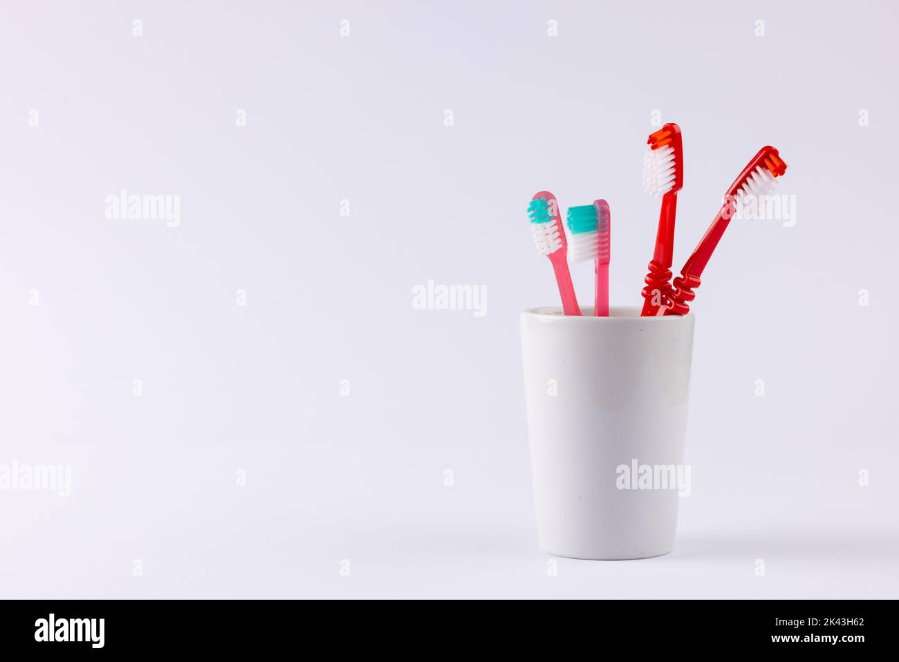 Immagine degli spazzolini da denti nella tazza su sfondo grigio Foto Stock