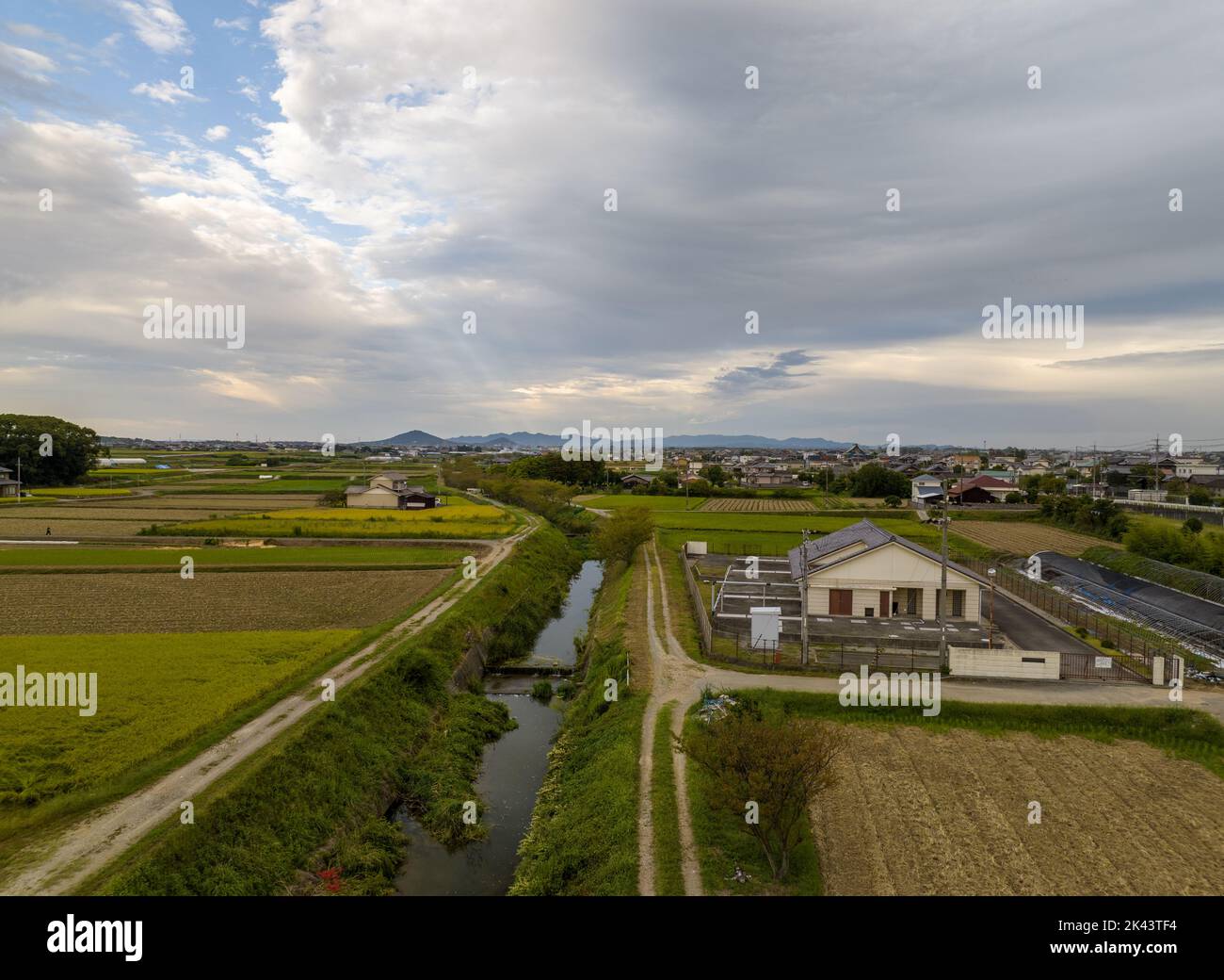 Fiume stretto fiancheggiato da strade sterrate da costruzione in zona agricola Foto Stock