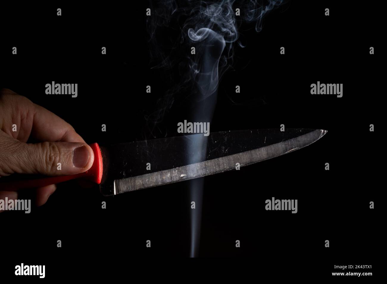 Un coltello in argento affilato su uno sfondo nero e fumo proveniente dal basso. Primo piano. Foto Stock