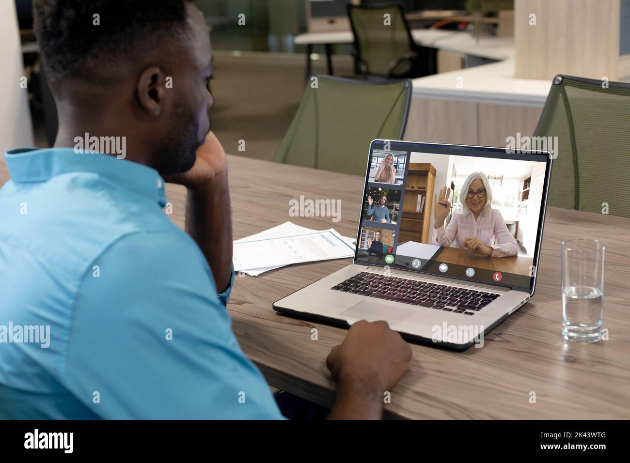 Composizione di un uomo d'affari afro-americano con videochiamata con i colleghi in carica. Concetto di interfaccia digitale e aziendale globale gener digitale Foto Stock