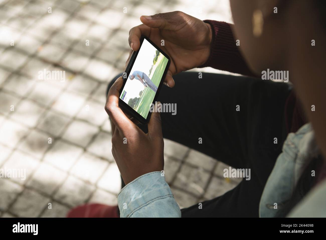 Uomo afroamericano nel parco che guarda il golf su smartphone. Sport, competizione, intrattenimento e tecnologia concetto immagine composita digitale. Foto Stock