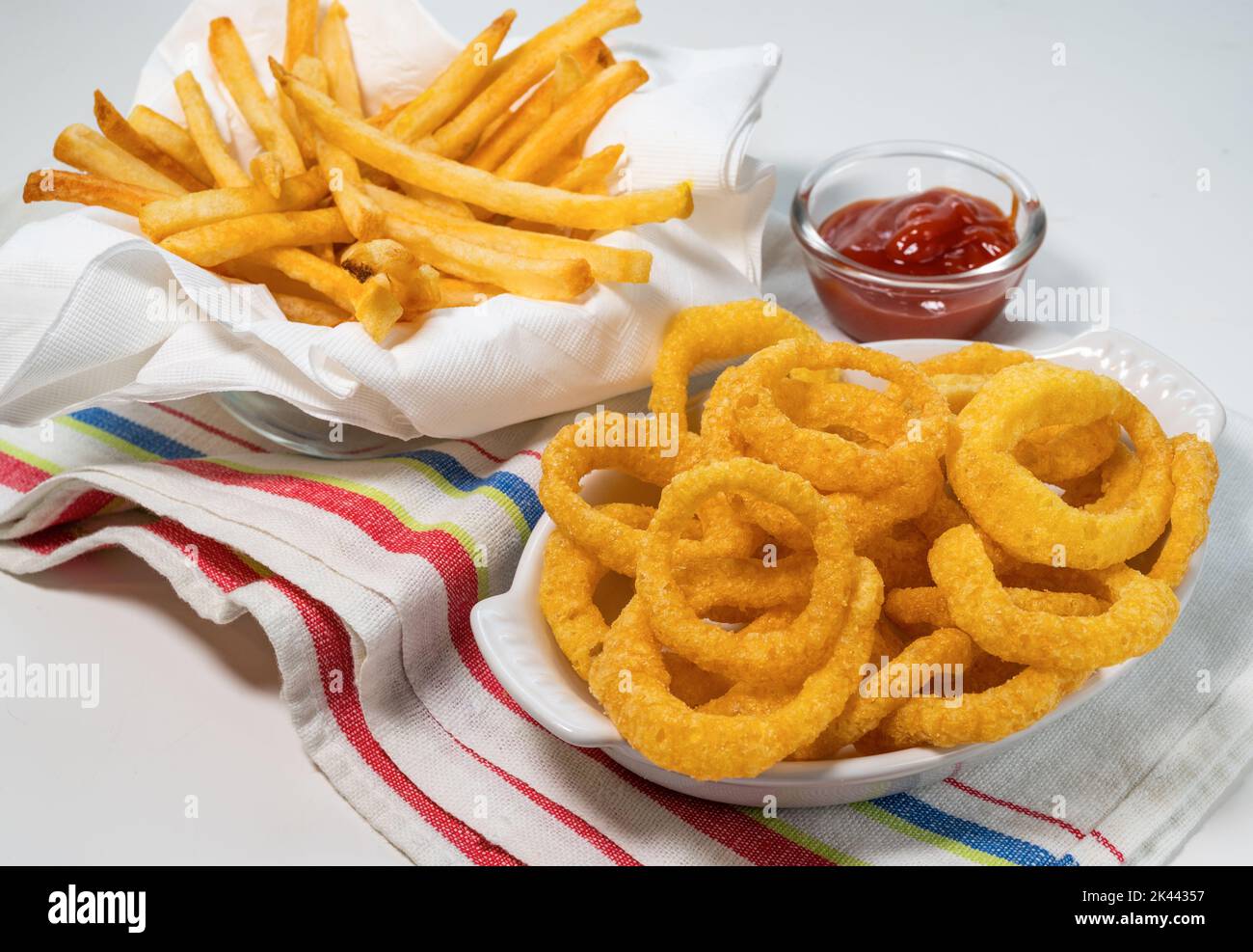 Anelli di cipolla fritti e patatine fritte con ketchup su tovaglia Foto Stock