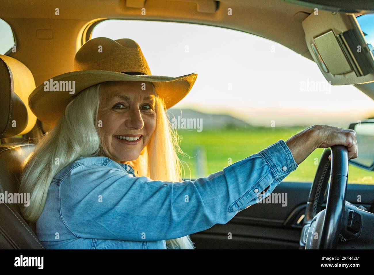Donna anziana in auto che indossa un cappello da cowboy Foto Stock