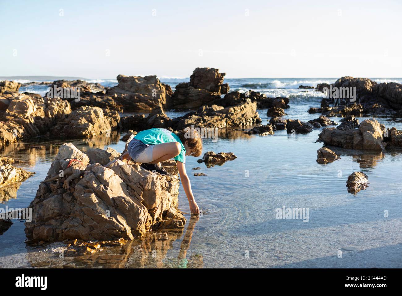 Sudafrica, Gansbaai, De Kelders, Boy (8-9) esplorando la costa rocciosa Foto Stock