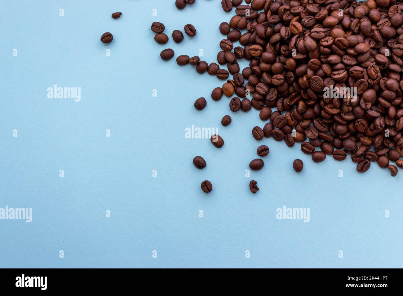 Mucchio di chicchi di caffè marrone scuro tostati su sfondo blu con spazio per le copie. Concetto di bevanda aromatica Foto Stock