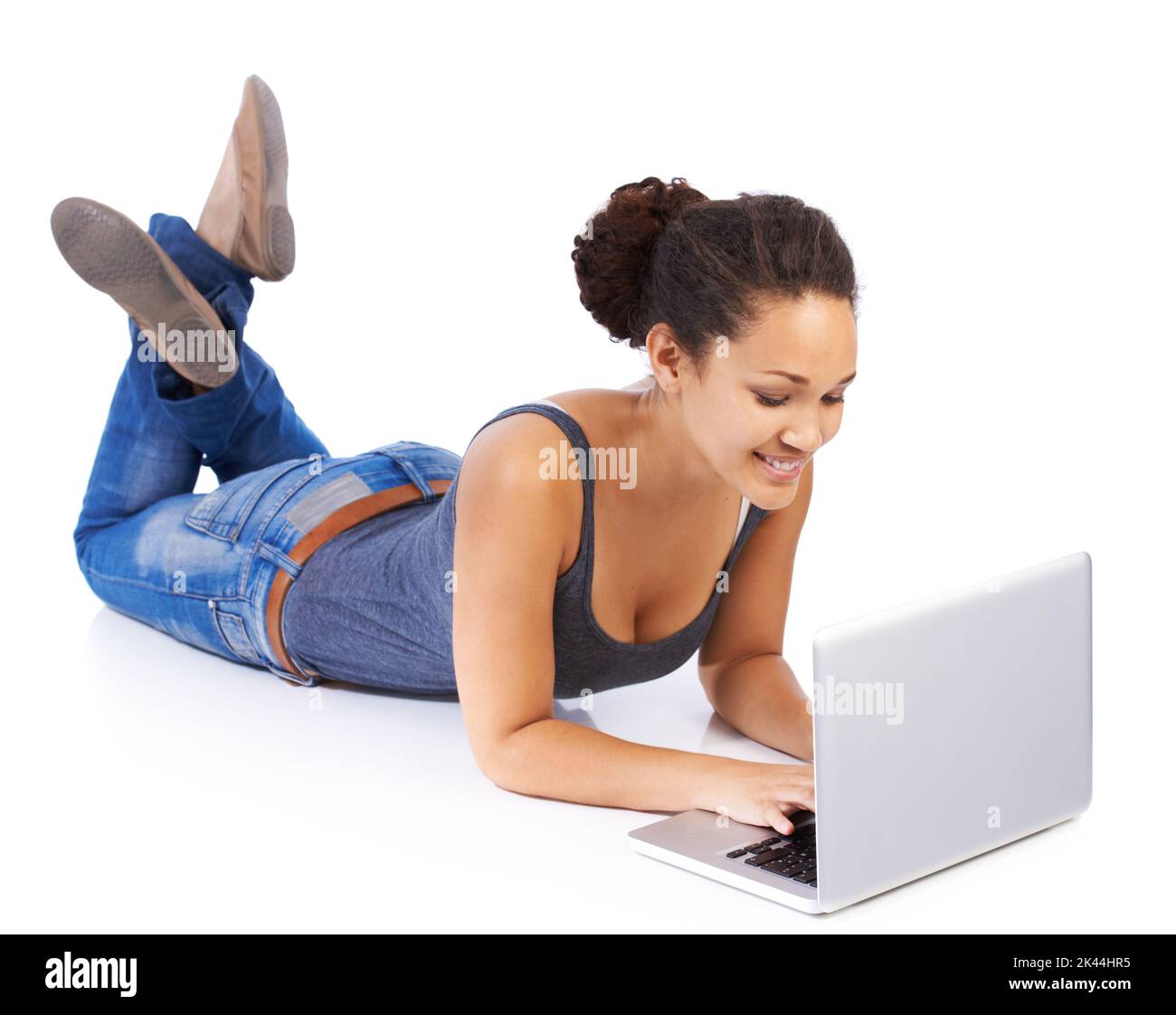 Godersi una chat online. Una bella giovane donna sdraiata sul pavimento e che usa il suo laptop su uno sfondo bianco. Foto Stock
