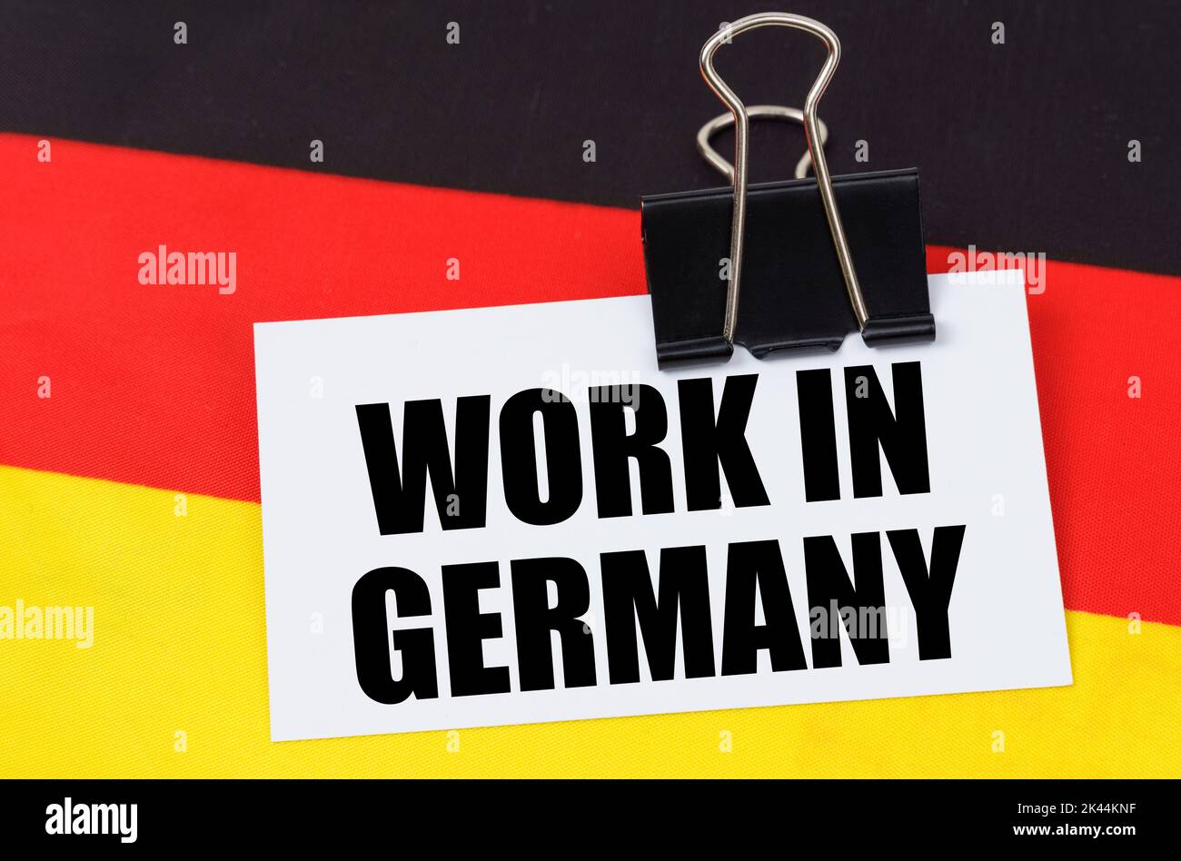 Concetto di economia nazionale. Sulla bandiera della Germania si trova un taccuino con l'iscrizione - lavoro in Germania Foto Stock