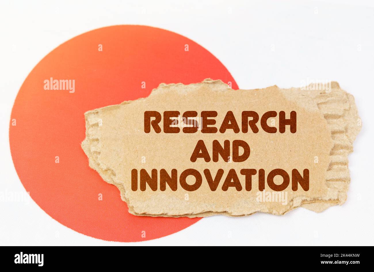 Concetto di economia nazionale. Sulla bandiera del Giappone si trova un notebook con l'iscrizione - Ricerca e innovazione Foto Stock